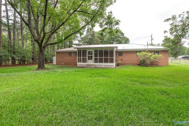 back of property with a sunroom and a lawn