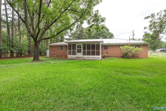 rear view of house featuring a sunroom and a yard