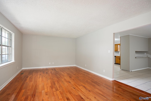 unfurnished room featuring light hardwood / wood-style flooring and a textured ceiling