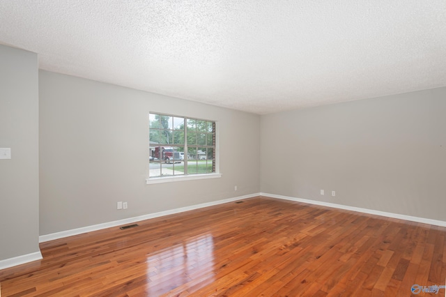 empty room featuring wood-type flooring and a textured ceiling