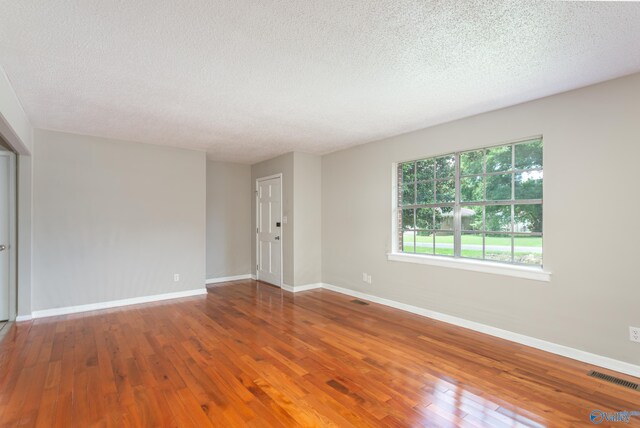 empty room with hardwood / wood-style floors and a textured ceiling