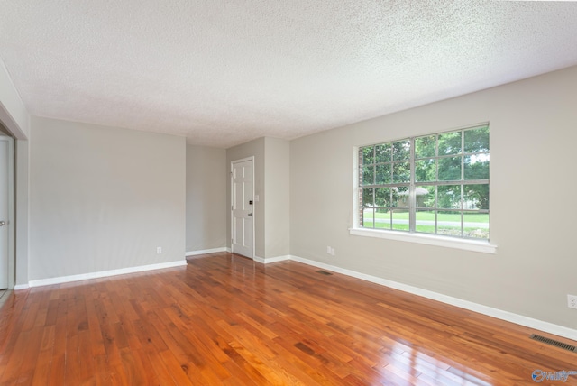 unfurnished room with hardwood / wood-style floors and a textured ceiling