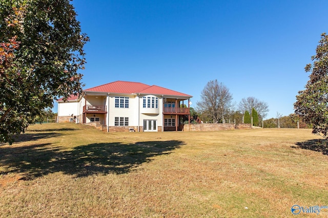 back of house with a yard and a balcony