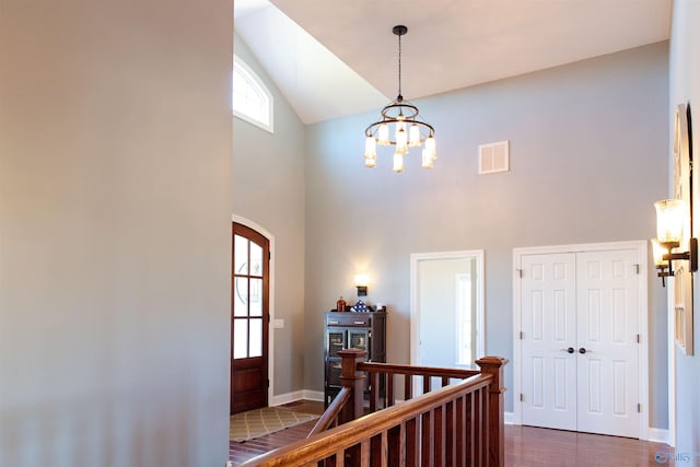 hall featuring dark hardwood / wood-style floors, a chandelier, and high vaulted ceiling