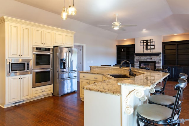 kitchen with sink, a breakfast bar area, pendant lighting, stainless steel appliances, and light stone countertops