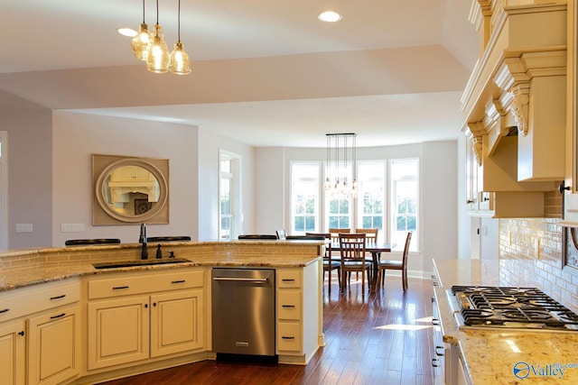 kitchen with light stone countertops, appliances with stainless steel finishes, sink, and decorative light fixtures