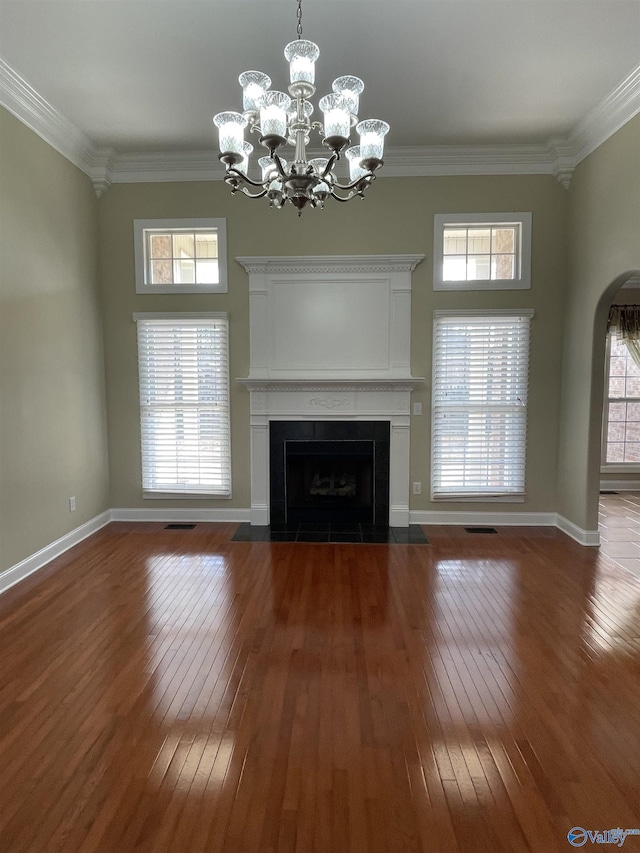 unfurnished living room featuring visible vents, a fireplace with flush hearth, ornamental molding, and hardwood / wood-style flooring