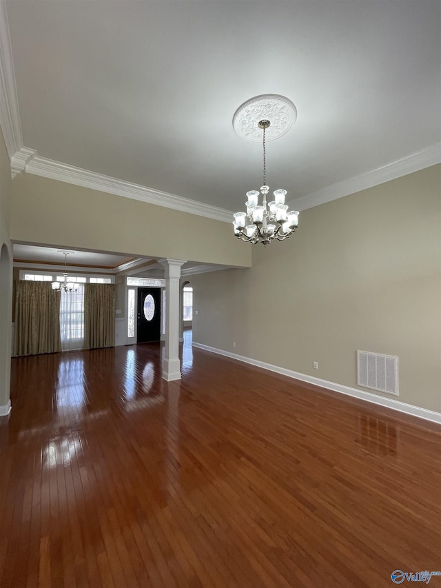 interior space featuring visible vents, hardwood / wood-style floors, ornamental molding, a notable chandelier, and ornate columns