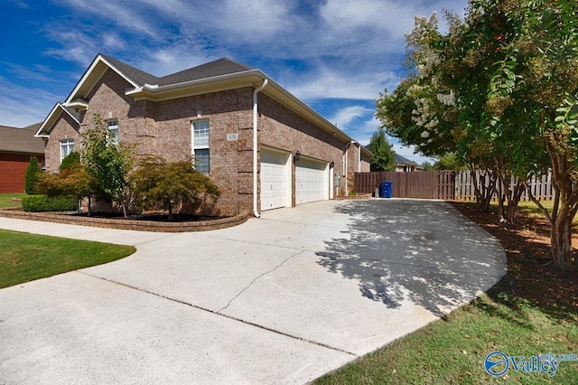 view of home's exterior featuring brick siding, an attached garage, driveway, and fence