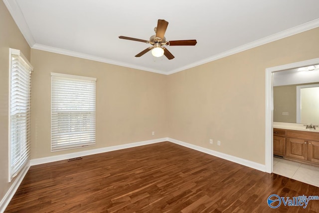 unfurnished bedroom featuring wood finished floors, visible vents, baseboards, a sink, and ornamental molding