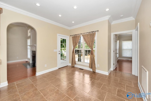 tiled spare room with a fireplace with flush hearth, crown molding, and baseboards