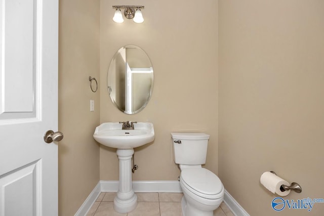 half bath featuring tile patterned flooring, toilet, and baseboards