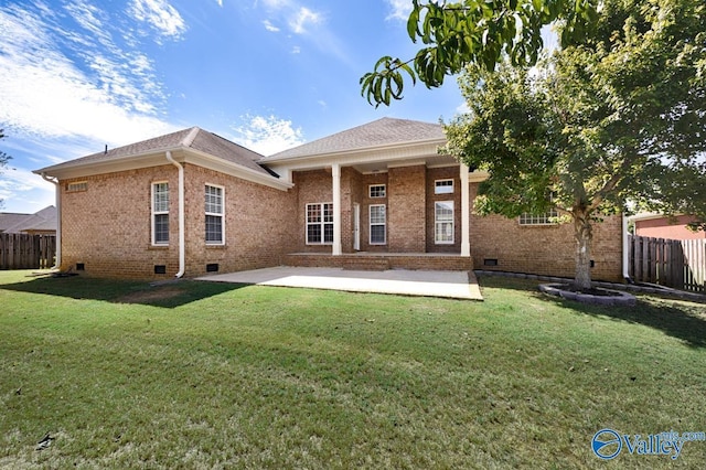 rear view of property featuring fence, brick siding, crawl space, a patio area, and a lawn