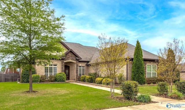 view of front of home featuring brick siding, a front yard, and roof with shingles