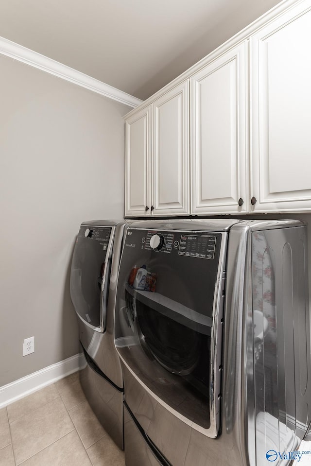 laundry area featuring crown molding, baseboards, cabinet space, and washer and clothes dryer