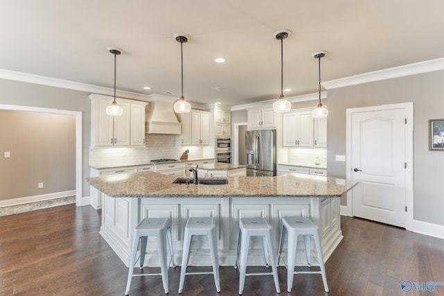 kitchen featuring a sink, a breakfast bar, appliances with stainless steel finishes, premium range hood, and a large island with sink
