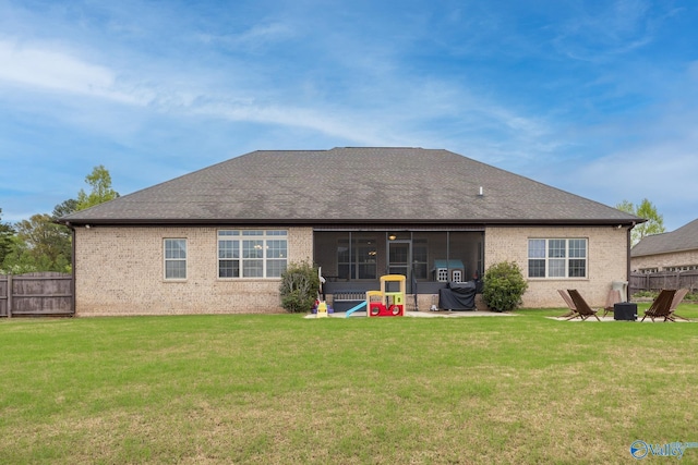 rear view of house with a yard, brick siding, and fence