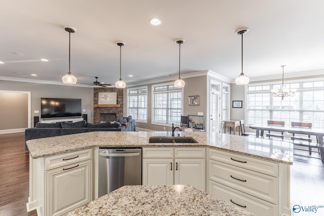 kitchen with ceiling fan with notable chandelier, a fireplace, ornamental molding, dishwasher, and a sink
