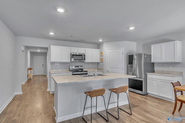 kitchen with sink, stainless steel appliances, light hardwood / wood-style floors, a kitchen island with sink, and white cabinets