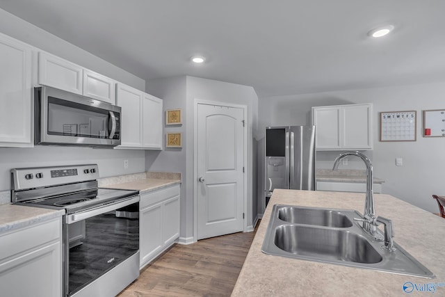 kitchen with white cabinets, stainless steel appliances, light hardwood / wood-style flooring, and sink