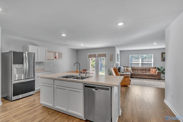 kitchen with sink, stainless steel appliances, light hardwood / wood-style floors, a kitchen island with sink, and white cabinets