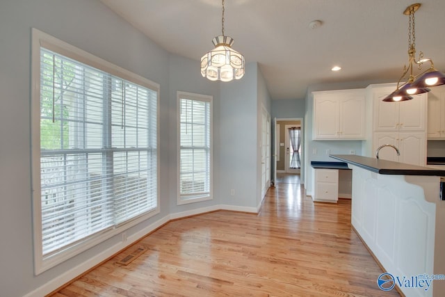 kitchen featuring plenty of natural light, dark countertops, visible vents, and light wood-style flooring