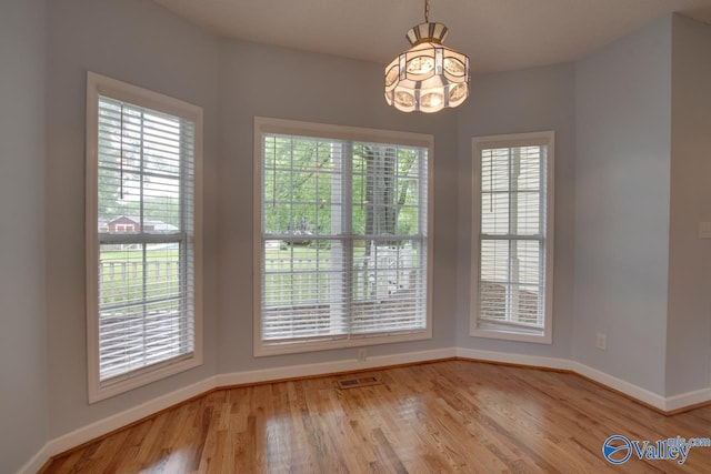 unfurnished dining area with visible vents, baseboards, a wealth of natural light, and an inviting chandelier