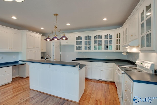 kitchen featuring dark countertops, under cabinet range hood, light wood-style floors, and white range with electric stovetop
