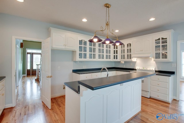 kitchen with white electric range oven, dark countertops, light wood-type flooring, and under cabinet range hood