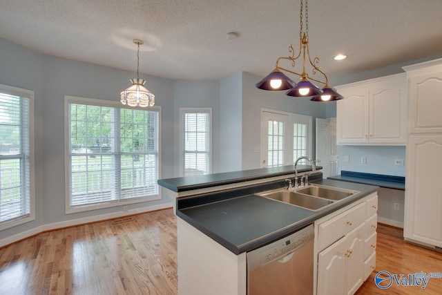 kitchen featuring white cabinets, stainless steel dishwasher, a sink, dark countertops, and an island with sink