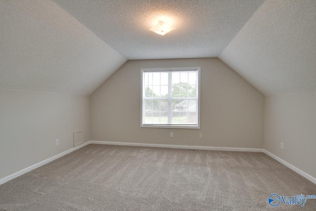 additional living space with lofted ceiling, carpet flooring, a textured ceiling, and baseboards