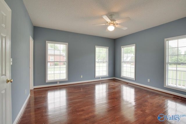 unfurnished room with baseboards, a ceiling fan, wood finished floors, and plenty of natural light