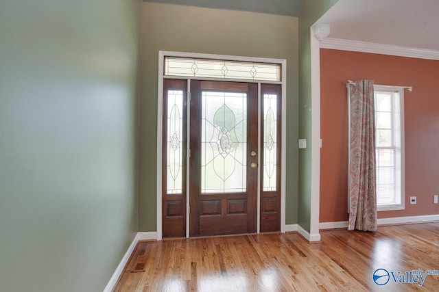 entrance foyer featuring light wood-style floors, visible vents, baseboards, and ornamental molding