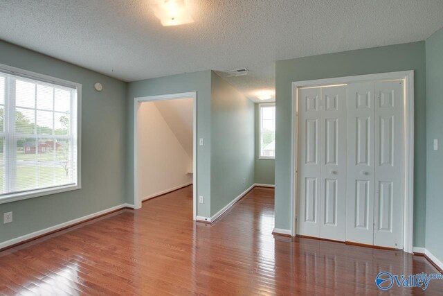 interior space with visible vents, baseboards, wood finished floors, and a textured ceiling