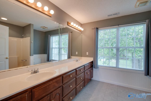 full bathroom with a sink, a wealth of natural light, walk in shower, double vanity, and visible vents