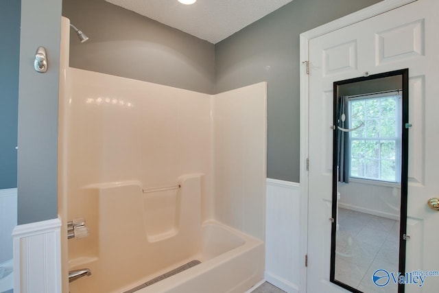 full bath featuring wainscoting, shower / bathtub combination, and a textured ceiling
