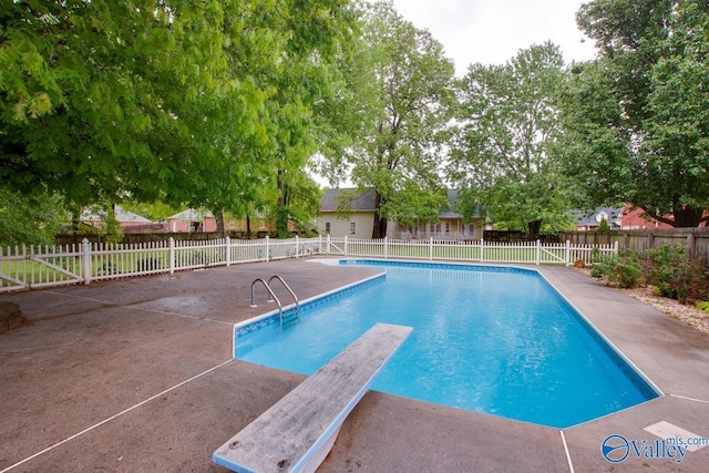 view of swimming pool featuring fence, a patio, a fenced in pool, and a diving board