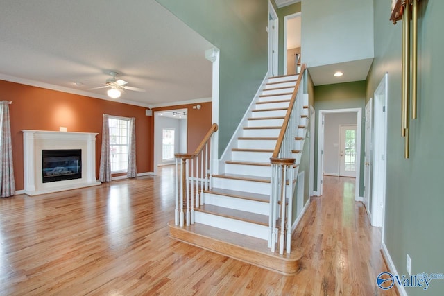stairs with baseboards, wood finished floors, and crown molding