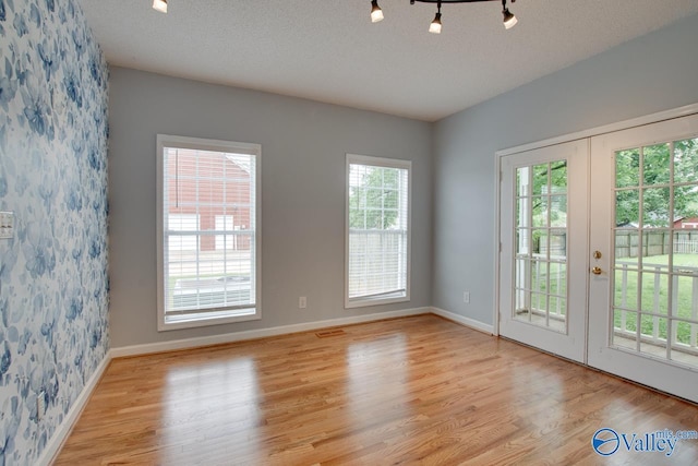 empty room featuring wood finished floors, baseboards, and french doors