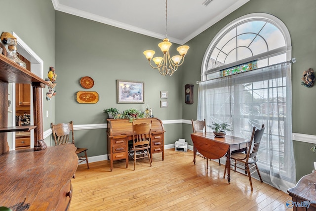 dining room with an inviting chandelier, ornamental molding, a towering ceiling, and light hardwood / wood-style floors