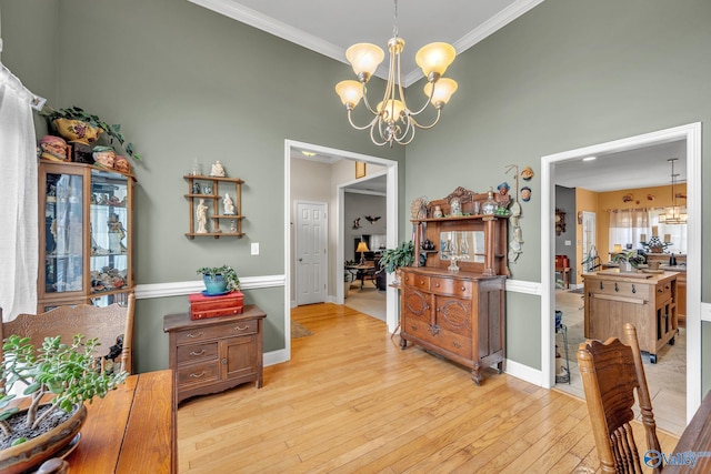 dining room with ornamental molding, a chandelier, light hardwood / wood-style flooring, and a high ceiling