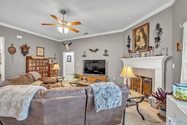 living room featuring ornamental molding, light colored carpet, a tile fireplace, and ceiling fan