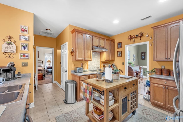 kitchen featuring sink, appliances with stainless steel finishes, decorative backsplash, and light tile patterned floors