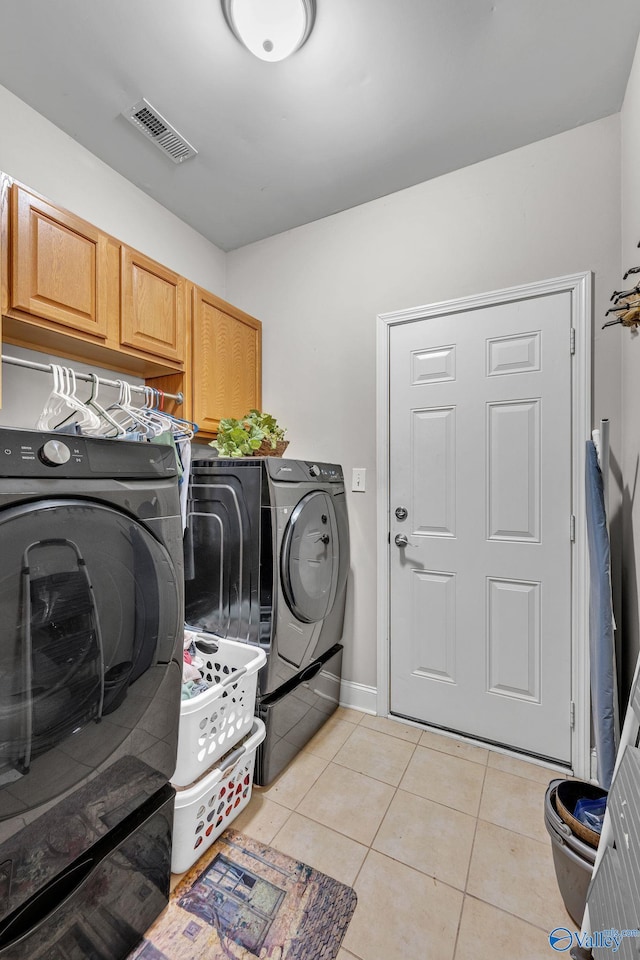 laundry area featuring washer and dryer, light tile patterned flooring, and cabinets