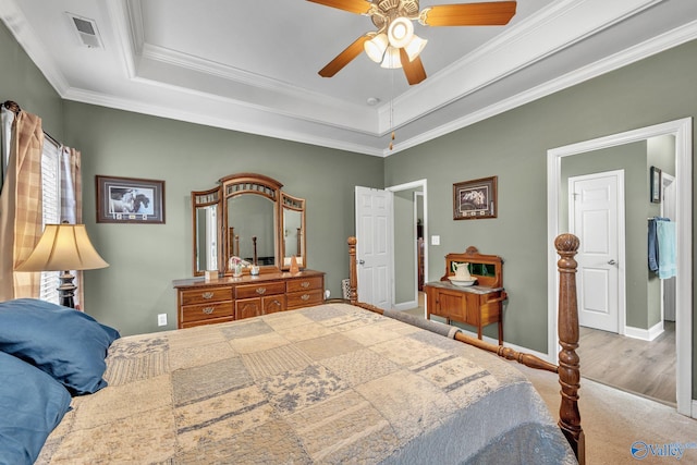 bedroom with ceiling fan, a raised ceiling, ornamental molding, and hardwood / wood-style floors