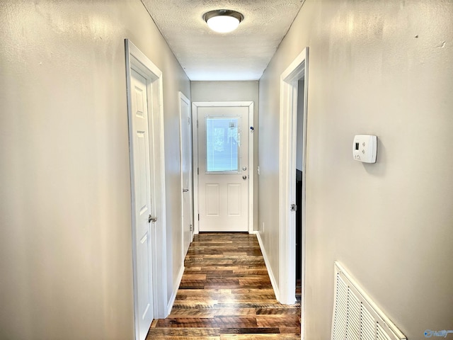 corridor featuring dark wood-type flooring and a textured ceiling