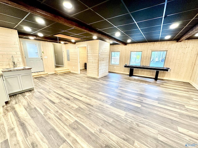 game room featuring wooden walls, light hardwood / wood-style flooring, a drop ceiling, and sink