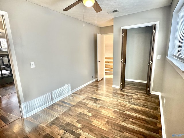 unfurnished bedroom featuring a textured ceiling, ceiling fan, and dark wood-type flooring