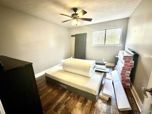 living area featuring ceiling fan, dark wood-type flooring, and a textured ceiling