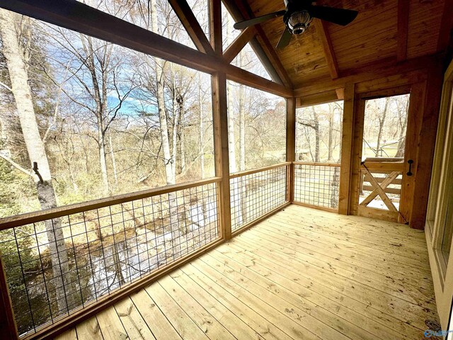 unfurnished sunroom with lofted ceiling with beams, plenty of natural light, ceiling fan, and wooden ceiling